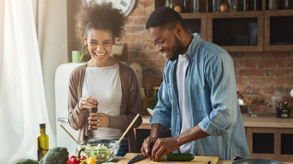 Couple improve intimacy by preparing a meal and a laugh together. In a rustic kitchen, representing everyday intimacy, shared routines, and emotional connection in relationship.