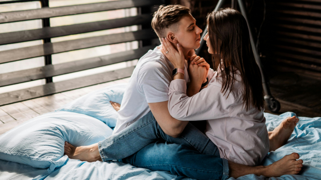 Couple sitting closely on a bed in an intimate pose, reflecting physical closeness, trust, and improving intimacy in therapy for relationships.