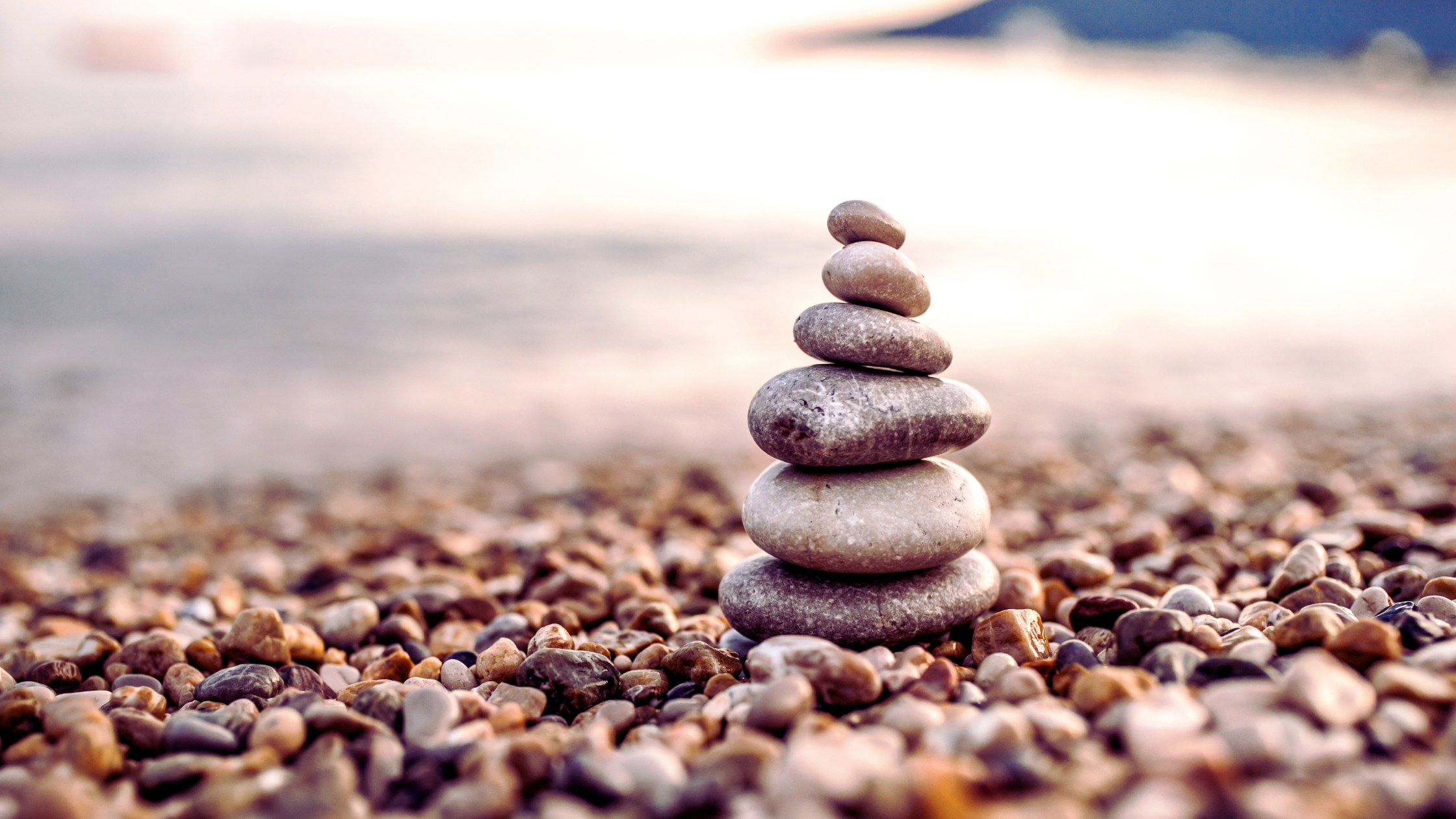 Stacked stones on a tranquil beach at sunset symbolizing emotional balance, relationship healing, and mindfulness—ideal visual for couples therapy intensive blog post.